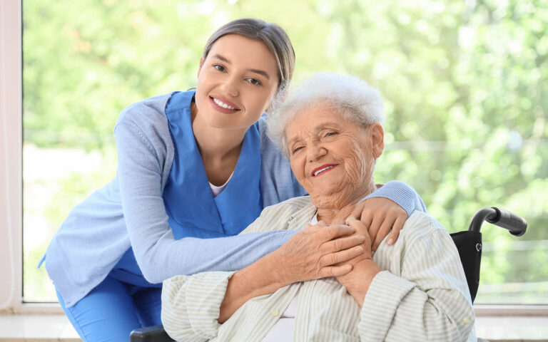 Nurse,Hugging,Senior,Woman,In,Wheelchair,Near,Window,At,Home